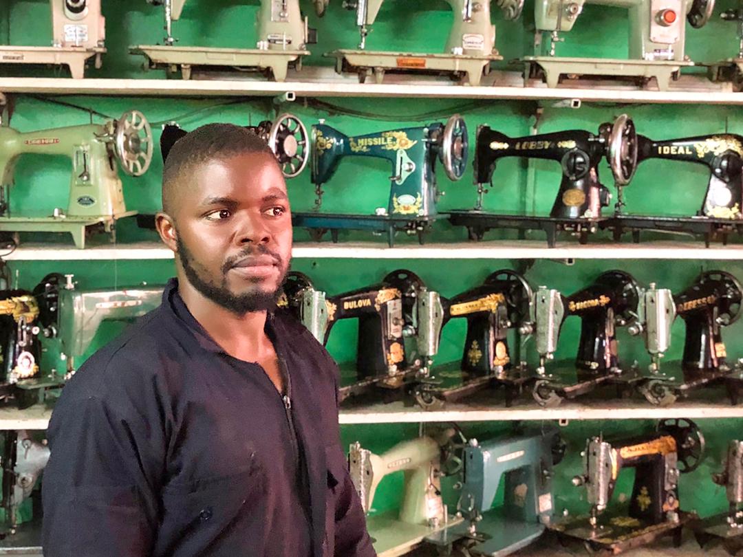 John Kigozi in front of his imported sewing machines
